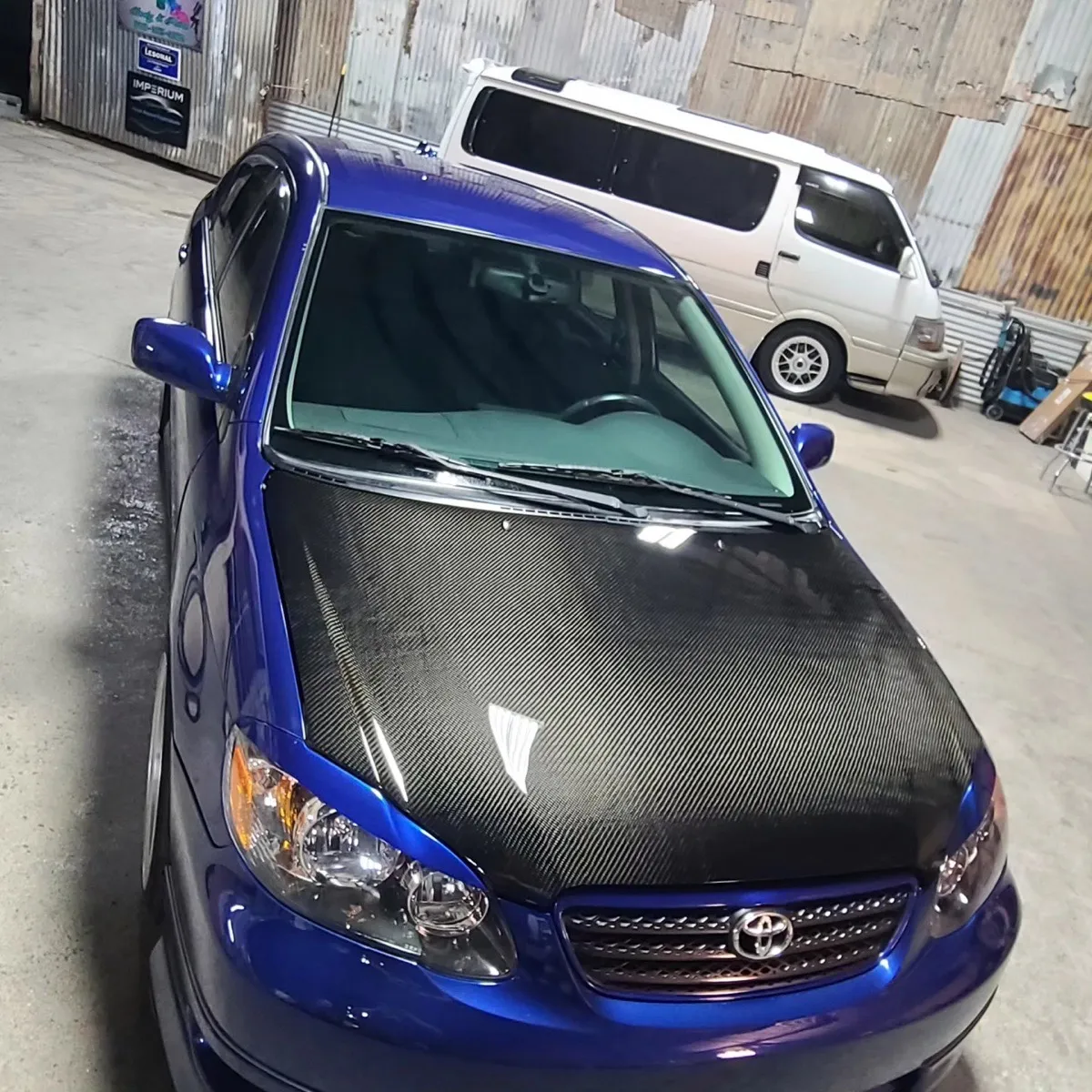 Restored carbon-fiber hood on a blue Toyota