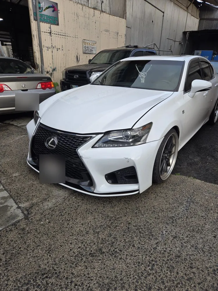 A clean white Lexus sedan, finished and parked at the shop