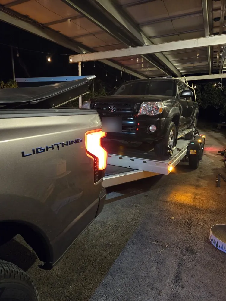 Electric pickup towing — The shop’s Ford F-150 Lightning pulling the trailer with an SUV on board.